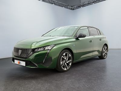 La voiture verte est garée dans une grande pièce aux murs blancs.