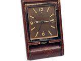 a small clock that is sitting on top of a leather case
