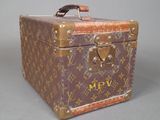 une valise marron et beige posée sur une surface grise