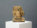 sculpture représentant un hibou doré posé sur un socle blanc, sur fond gris