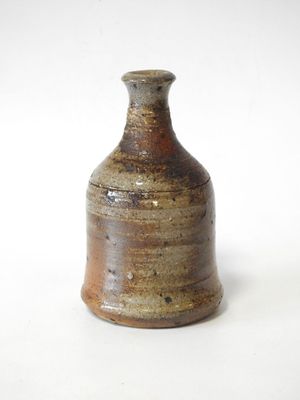 un petit vase brun posé sur une surface blanche