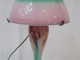 une lampe verte et rose posée sur une table blanche