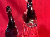 deux figurines en verre représentant un chien et un oiseau assis sur une chaise