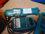 a blue electric drill and some other tools on the floor