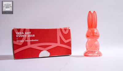un petit lapin en plastique posé à côté d'une boîte rouge
