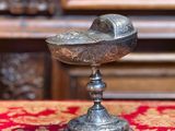 un bol en argent posé sur une nappe rouge, à côté de quelques noix