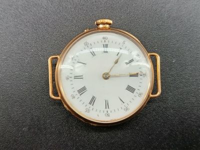 une petite montre de poche en or dont le cadran est orné de chiffres romains