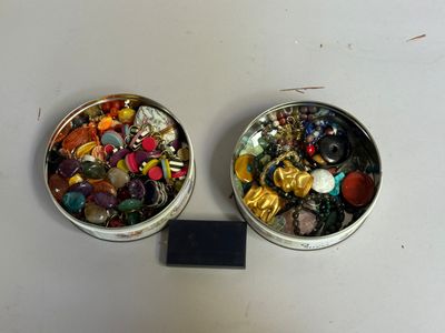 deux boîtes remplies de boutons de différentes couleurs posées sur une table