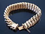 a close up of a gold bracelet with a lock on a black surface