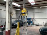 Les voitures sont garées dans un garage où se trouve une grue au milieu de la pièce.