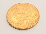 a gold coin with a bird on it on a white surface