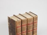 three old books sitting on top of each other on a white surface