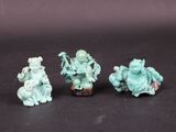 three small figurines of people sitting on a black surface