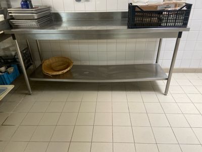a stainless steel table with a basket on top of it in a kitchen