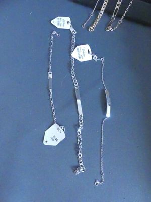 a lot of silver necklaces and bracelets on a table
