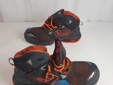 pair of black and orange shoes with orange laces and a tennis ball