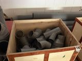 une boîte remplie de raccords de tuyauterie posée par terre
