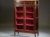 une bibliothèque ancienne en acajou, ornée de montures en laiton et recouverte de velours rouge