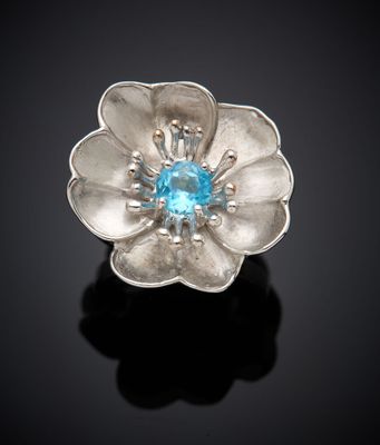 un gros plan sur une bague en forme de fleur sertie d'une topaze bleue
