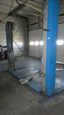 un garage avec un pont élévateur bleu au milieu