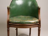 a green leather chair with a wooden frame and wooden legs