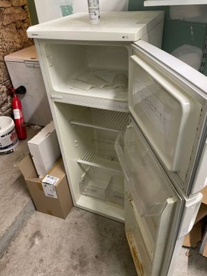 un réfrigérateur blanc dont la porte est ouverte, dans une pièce