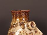a brown vase with a bird on it sitting on a table