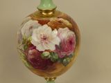 a vase with flowers painted on it sitting on a table