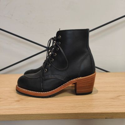 une paire de bottes en cuir noir posée sur une étagère en bois