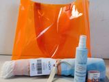 un sac orange contenant une serviette, un flacon de crème solaire et un flacon de crème solaire