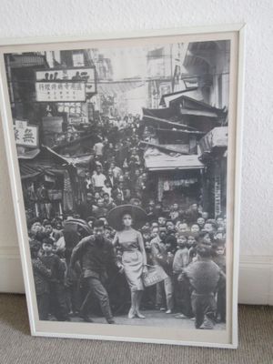 une photo en noir et blanc montrant une foule de personnes marchant dans une rue