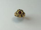 gros plan d'une bague en or avec une pierre rouge au centre