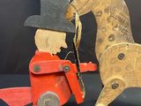 a wooden toy horse with a man in a top hat and red coat