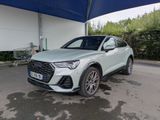 une Audi QX blanche garée devant un garage