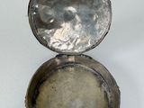 a small silver box with a lid on a white surface