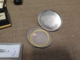 a small compact mirror sitting on the floor next to a pen