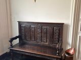 un banc en bois dans un coin d'une pièce où se trouve un lustre