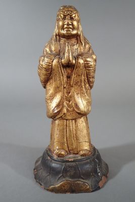 statue en or représentant une femme, les mains jointes, assise sur un rocher