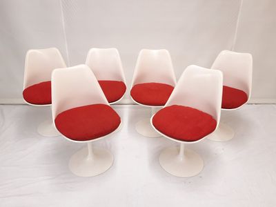 quatre chaises « Tulip » blanches avec des coussins rouges dans une pièce blanche