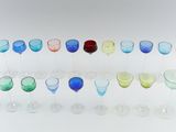 many different colored wine glasses lined up on a table
