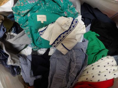 une boîte blanche remplie de vêtements et des vêtements par terre