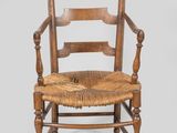 an old wooden chair with a woven seat on a gray background