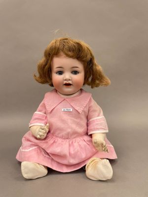 une image représentant une petite poupée assise sur une surface grise