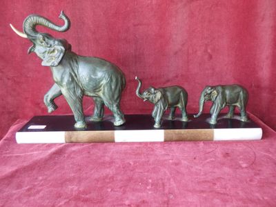une statue représentant un éléphant et deux éléphanteaux, posée sur un socle