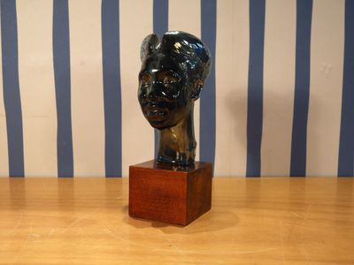 une statue représentant la tête d'une femme, posée sur un socle en bois