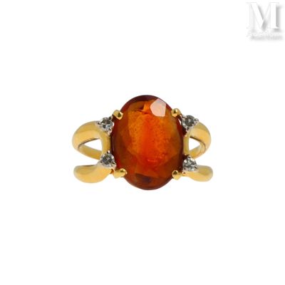 un gros plan d'une bague sertie d'une pierre orange et de diamants