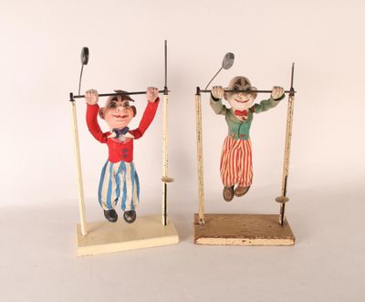 une paire de figurines vintage représentant des clowns, posées sur des socles en bois, sur fond blanc