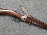 an old rifle with a wooden handle on a gray surface