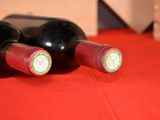 two bottles of wine sitting on a red cloth