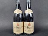 two bottles of red wine sitting next to each other on a table